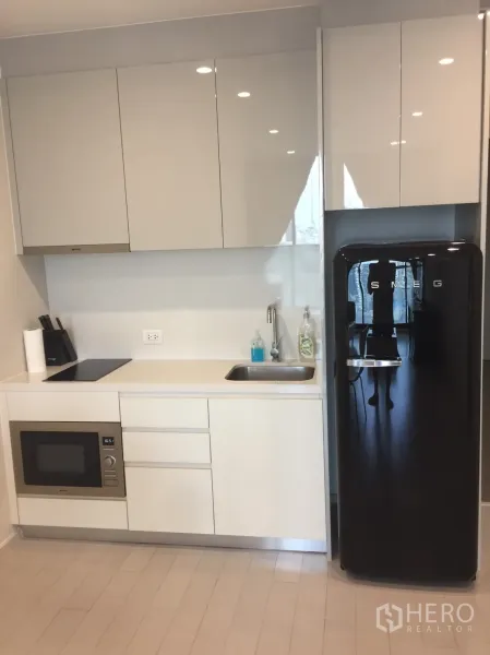 คอนโด ให้เช่าในPathum Wan, Bangkok - ครัวบิวท์อินสไตล์โมเดิร์น ตู้แขวนเงา เตาไฟฟ้า ไมโครเวฟ และตู้เย็น SMEG สีดำ