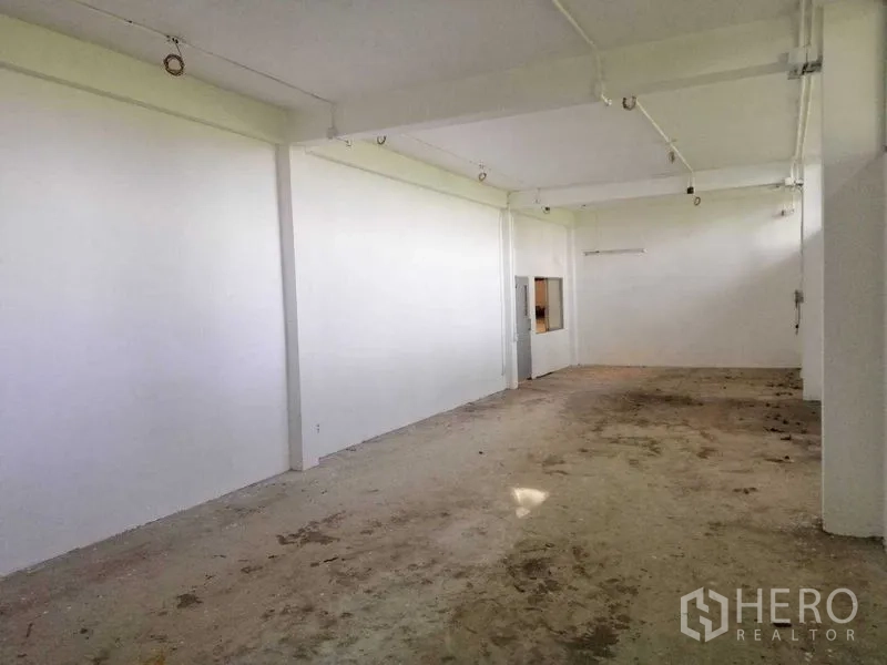 Factory for rent in Pathum Thani - Another angle of the white utility room showing an electrical panel and internal service window.