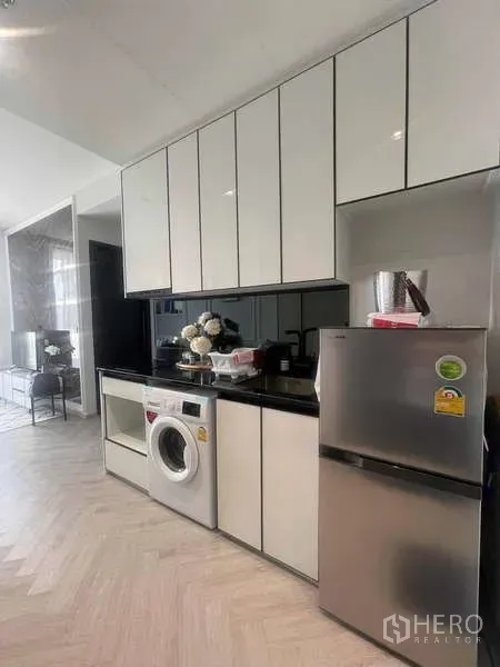 คอนโด ให้เช่า - ครัวสมัยใหม่ตู้สีขาวเงา ท็อปหินสีดำ มีเครื่องซักผ้าและตู้เย็นสแตนเลส