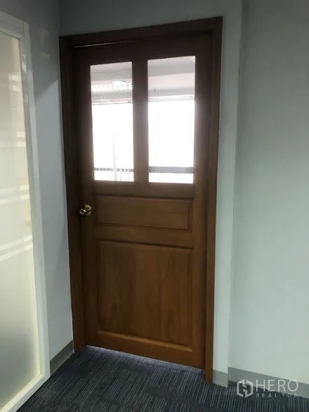 สำนักงาน ให้เช่า - ประตูไม้กระจกใสข้างฉากกระจกฝ้าในโถงสำนักงานปูพรม