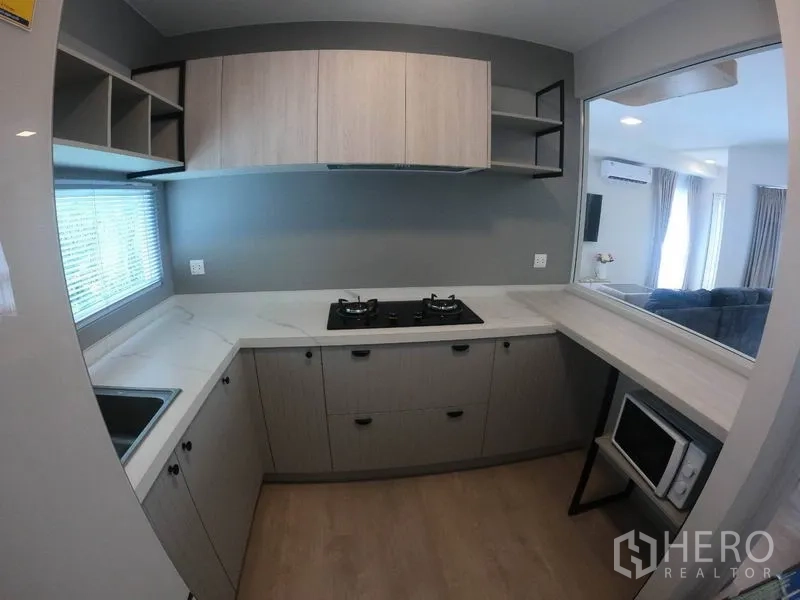 Detached House for rent in Prawet, Bangkok - Kitchen with serving window to living area, built-in storage and microwave shelf.