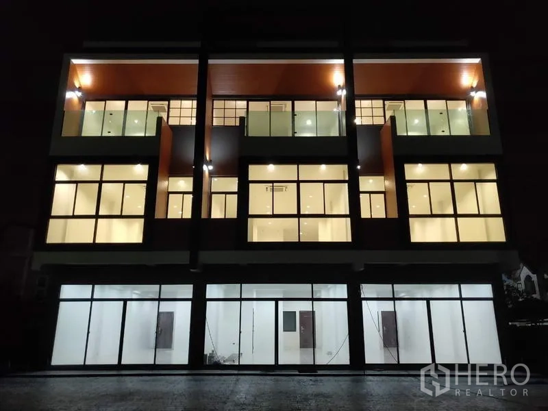 Home Office for sale in Lam Luk Ka, Pathum Thani - Night view of the illuminated three-storey home office with glass storefronts.