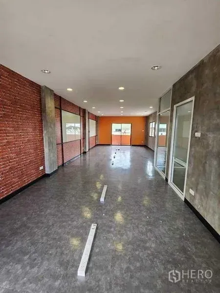 Office Space for rent or sale in Bueng Kum, Bangkok - Open-plan office floor featuring exposed brick, polished flooring, recessed lighting and a glass-partitioned room at the end.