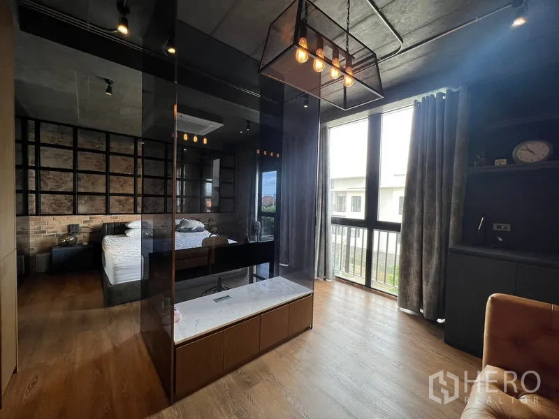 联排别墅 出租在Saphan Sung, Bangkok - 主套房设玻璃隔断、吊灯与大窗户，木地板。