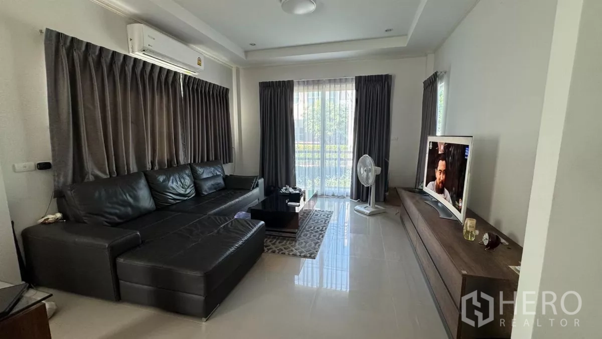 บ้าน ขายในLat Krabang, Bangkok - ห้องนั่งเล่นสว่าง โซฟาหนังสีดำ ชั้นวางทีวี พื้นกระเบื้อง ประตูกระจกสไลด์ออกสู่สวน