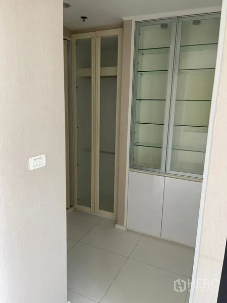 Condominium for sale in Suan Luang, Bangkok - Walk-in storage zone with glass display cabinet and tall wardrobes in neutral tones.
