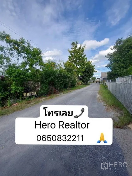 货栈 出租在Nakhon Pathom - 通往仓库的宁静道路，两侧绿植与铁丝网围栏，天空晴朗。