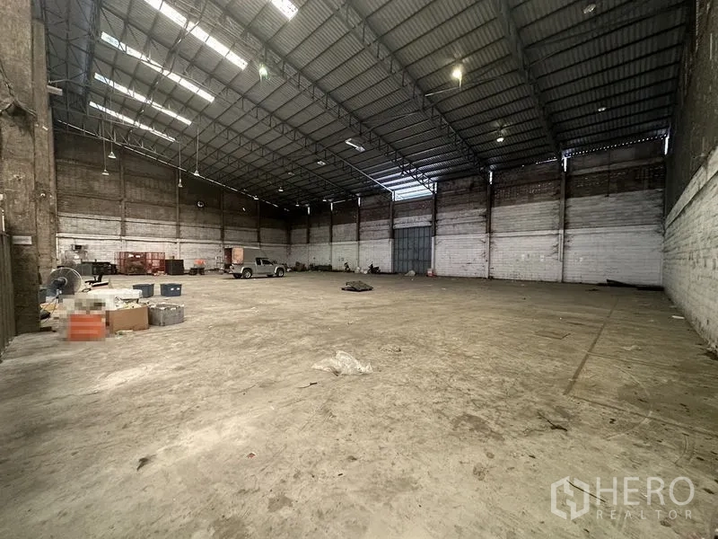 Warehouse for rent in Suan Luang, Bangkok - Open storage hall featuring a high-clear ceiling, concrete floor and a large sliding door.