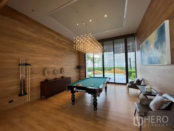 คอนโด ขาย - ห้องพักผ่อนพร้อมโต๊ะพูล โคมไฟระย้า ผนังลายไม้และวิวสวน