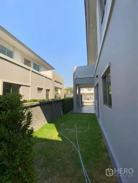 บ้าน ให้เช่า - สวนข้างบ้านแนวยาว มีพุ่มไม้ สนามหญ้า และสายยาง