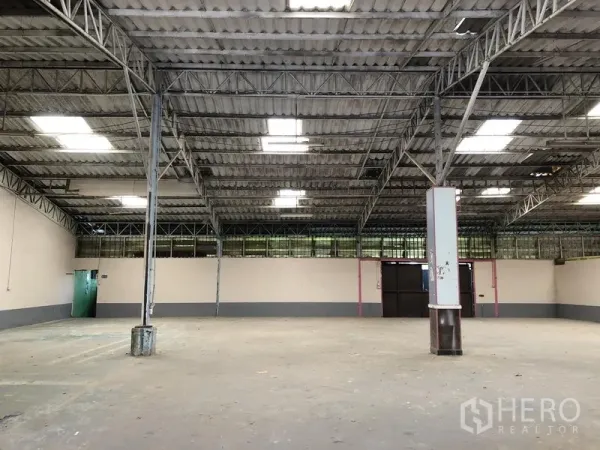 Warehouse for rent in Sai Mai, Bangkok - Spacious warehouse interior featuring a steel truss roof, skylights, and an open concrete floor.