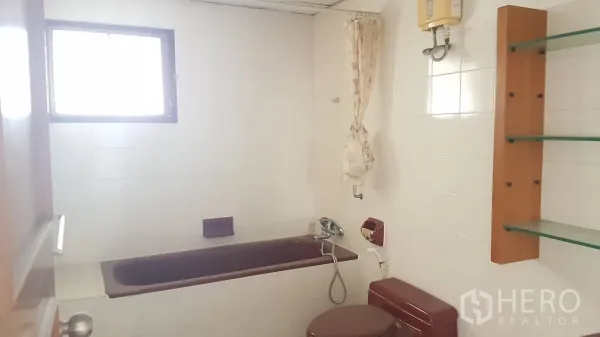 คอนโด ให้เช่าในKhlong Toei, Bangkok - ห้องน้ำกระเบื้องขาว พร้อมอ่างอาบน้ำและโถสุขภัณฑ์สีม่วงแดง มีชั้นกระจกและหน้าต่าง