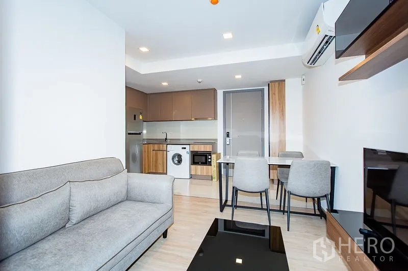 คอนโด ให้เช่าในWatthana, Bangkok - พื้นที่นั่งเล่นแบบโอเพ่นแพลนหันเข้าครัวบิลต์อินและชุดทานอาหาร พร้อมแอร์และไฟดาวน์ไลท์