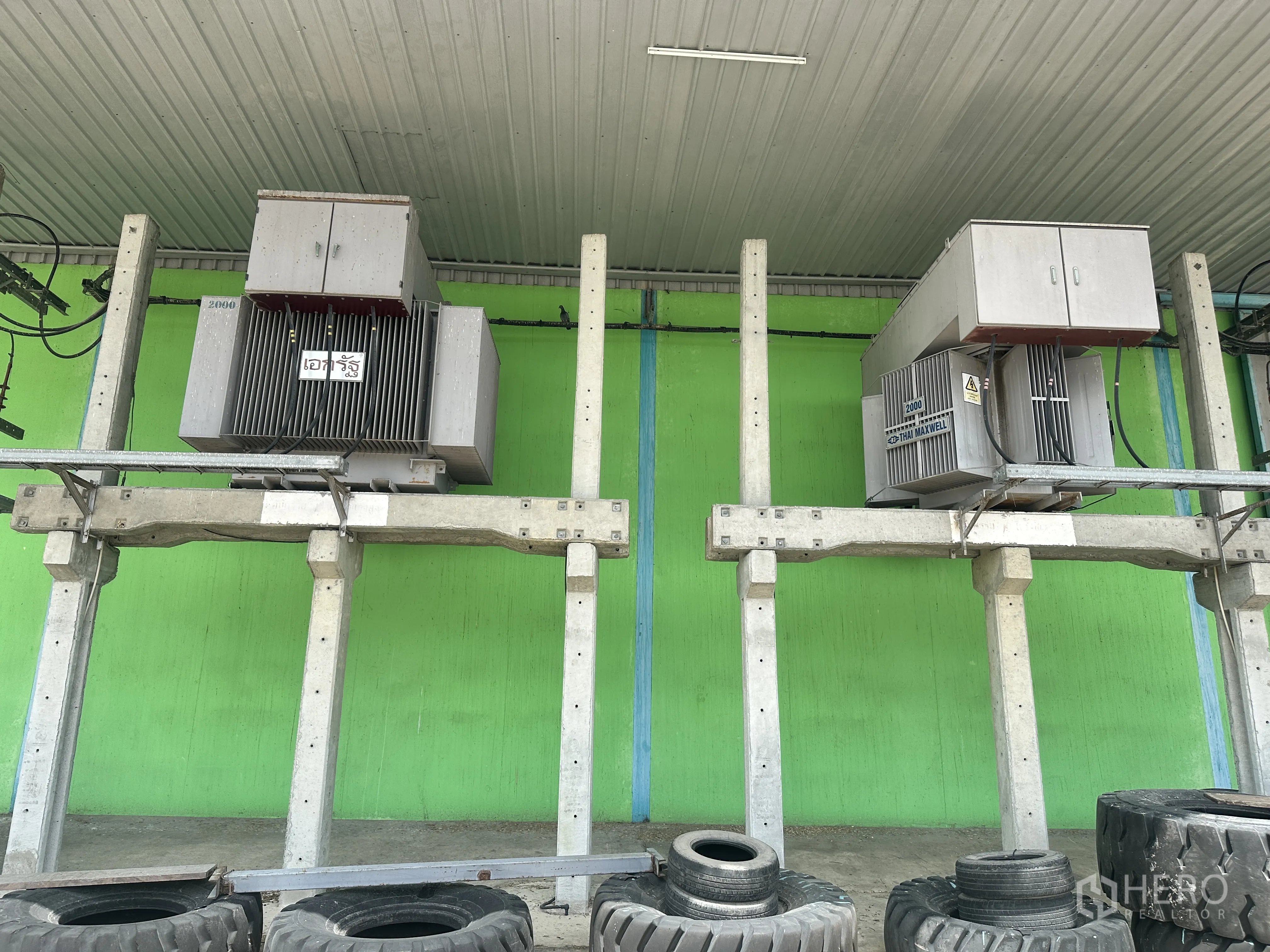 仓库 for rent in Sai Noi, Nonthaburi - 两台安装在高架支座上的电力变压器特写。