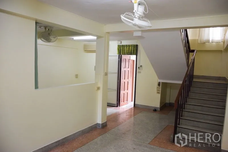 联排别墅 出租在Watthana, Bangkok - 一层走厅，带吊扇与室内楼梯。