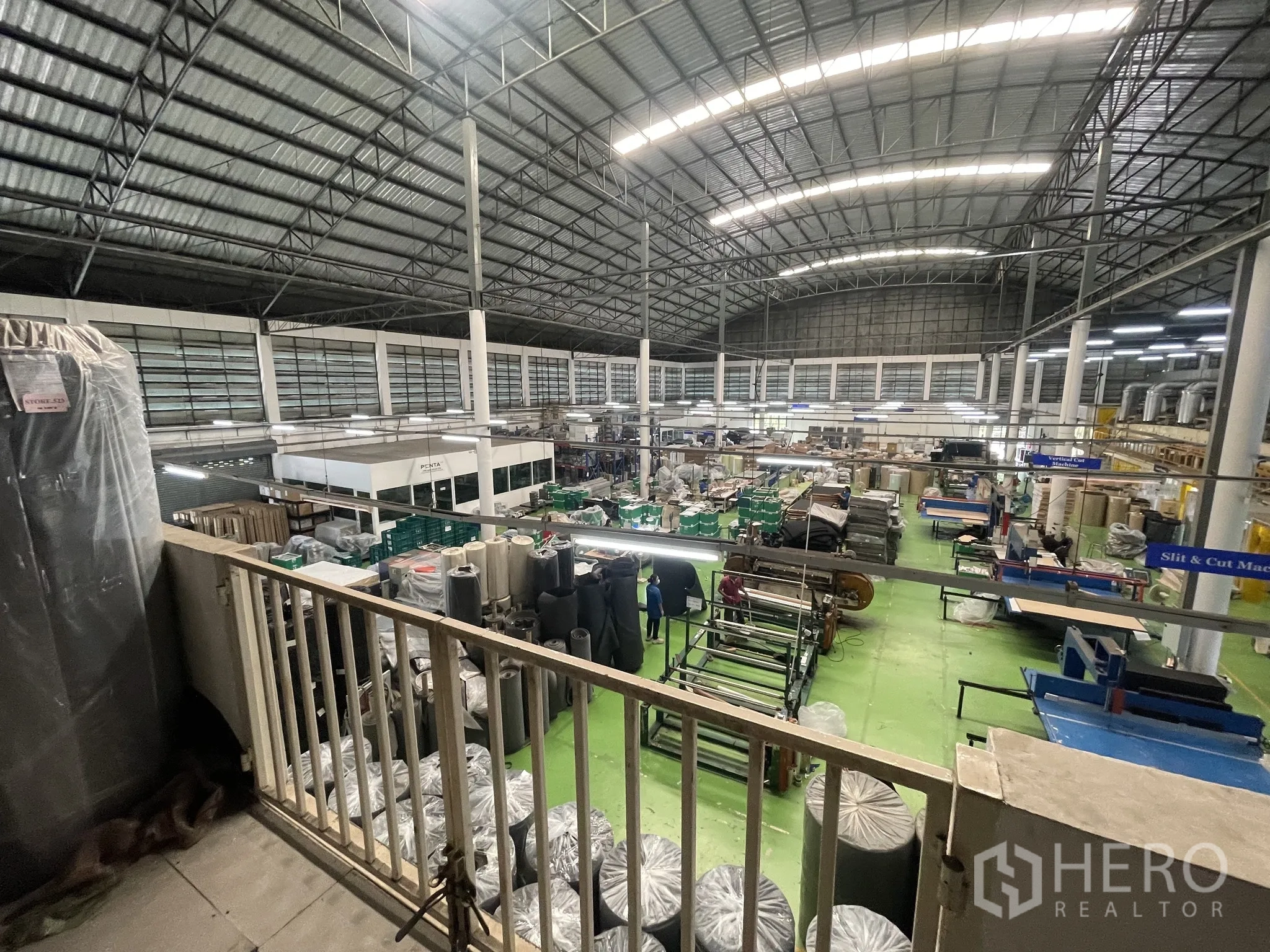 Warehouse for sale in Lat Lum Kaeo, Pathum Thani - Elevated view of the spacious warehouse floor showing equipment and workstations.