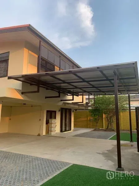 独立式住宅 出租或出售在Phra Khanong, Bangkok - 两层住宅配金属雨棚、铺装车道和人工草坪。