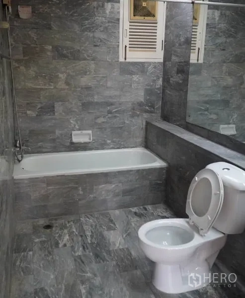 Townhouse for rent in Pathum Wan, Bangkok - Gray-tiled bathroom with bathtub, shower and large mirror.
