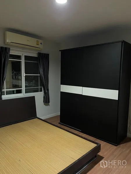 Detached House for rent in Bang Kapi, Bangkok - Bedroom with dark sliding wardrobe, split A/C and platform bed by the window.