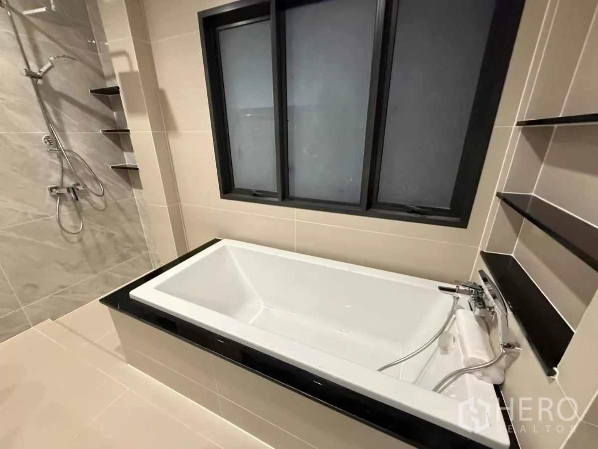 Detached House for rent in Bang Phli, Samut Prakan - Close-up of white bathtub beside window and shelving.