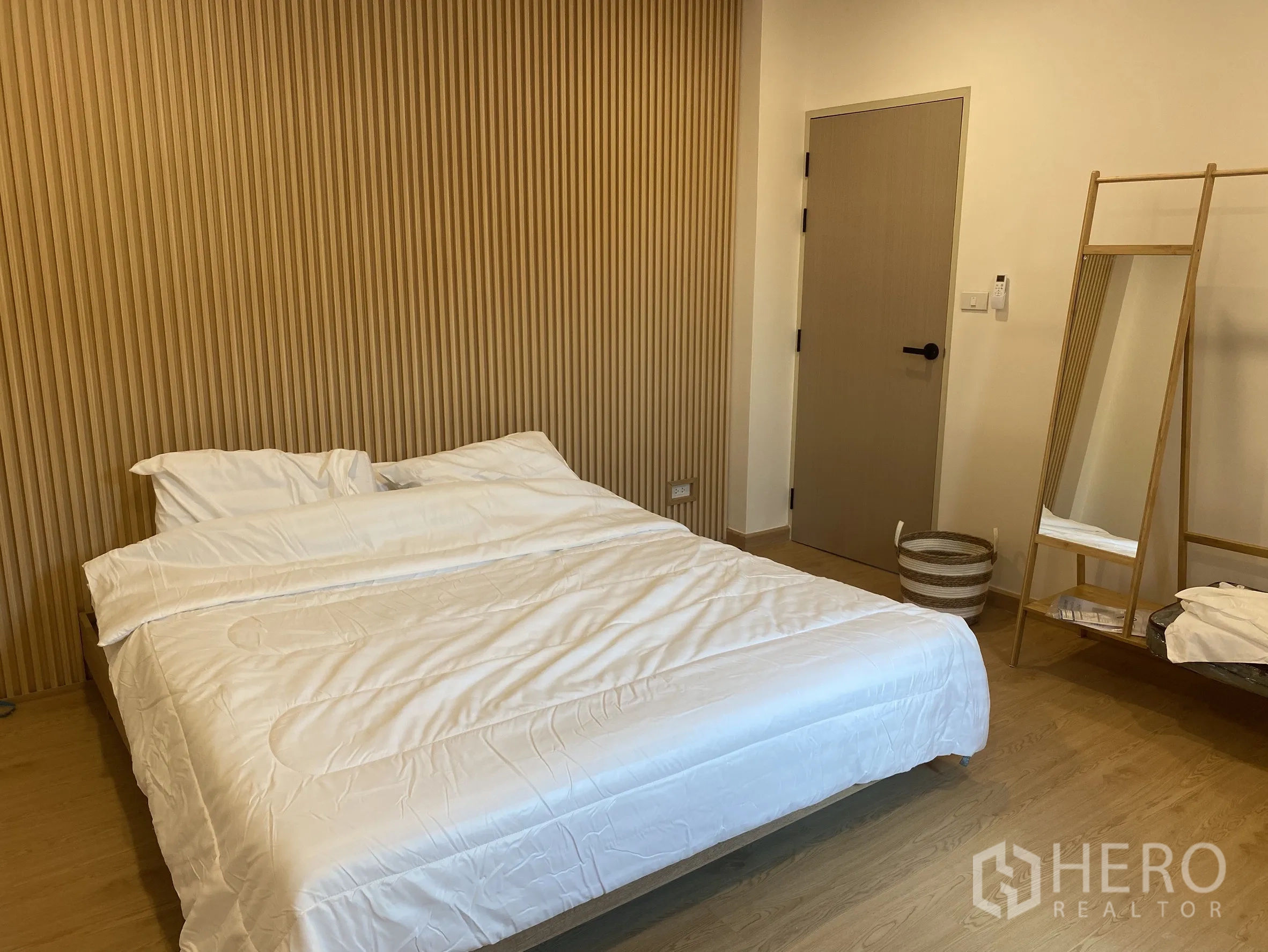 独立式住宅 出售在Suan Luang, Bangkok - 温馨卧室，竖向木条背景墙与立式镜架。