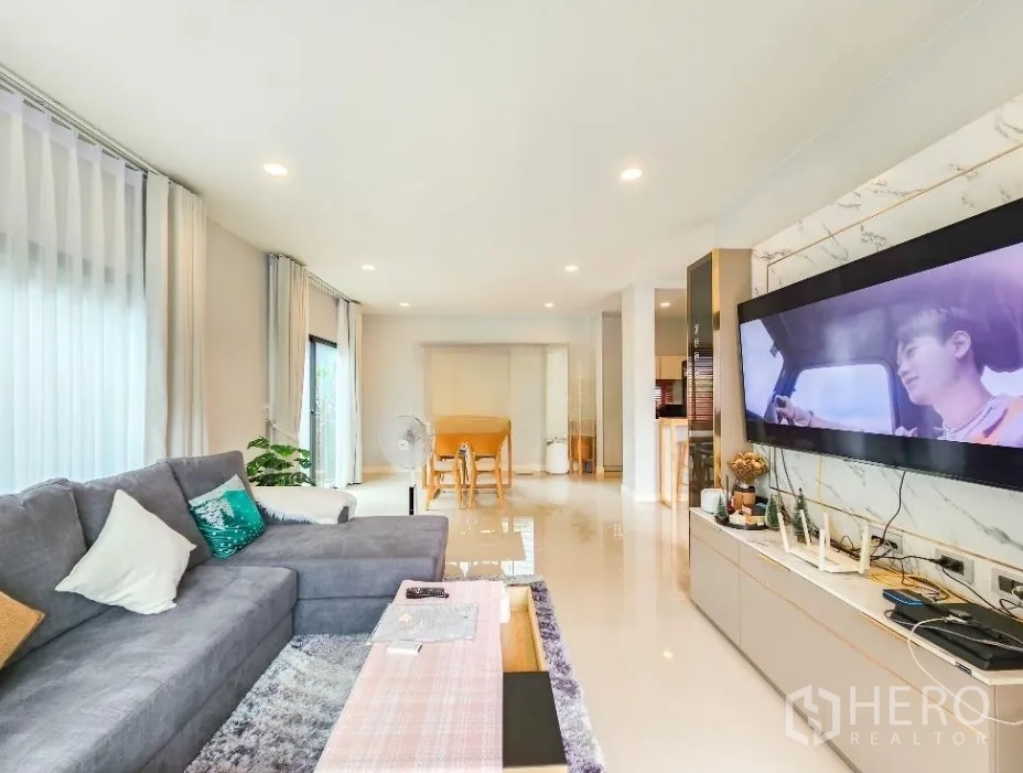 บ้าน ขายในLam Luk Ka, Pathum Thani - โถงนั่งเล่นแบบเปิดเชื่อมทีวีจอใหญ่ติดผนัง พื้นกระเบื้องมันเงา