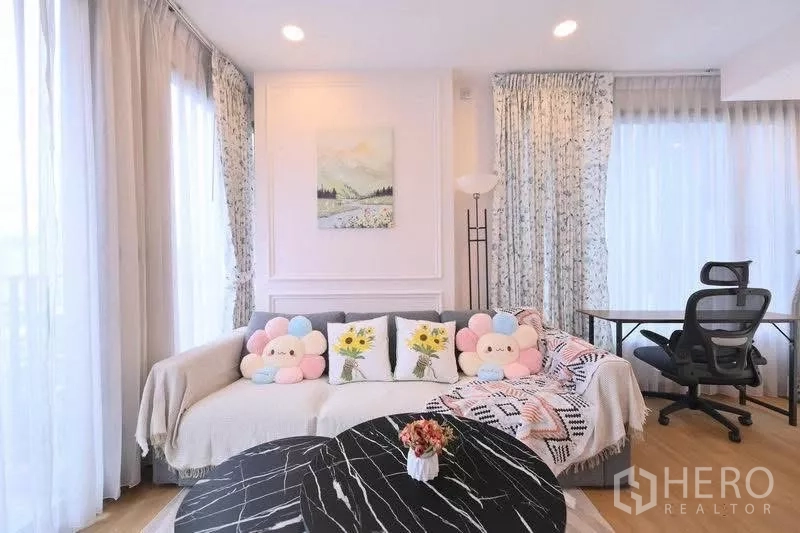 Condominium for rent in Watthana, Bangkok - Corner living area with sofa, colorful cushions and a dedicated work desk by panoramic windows.