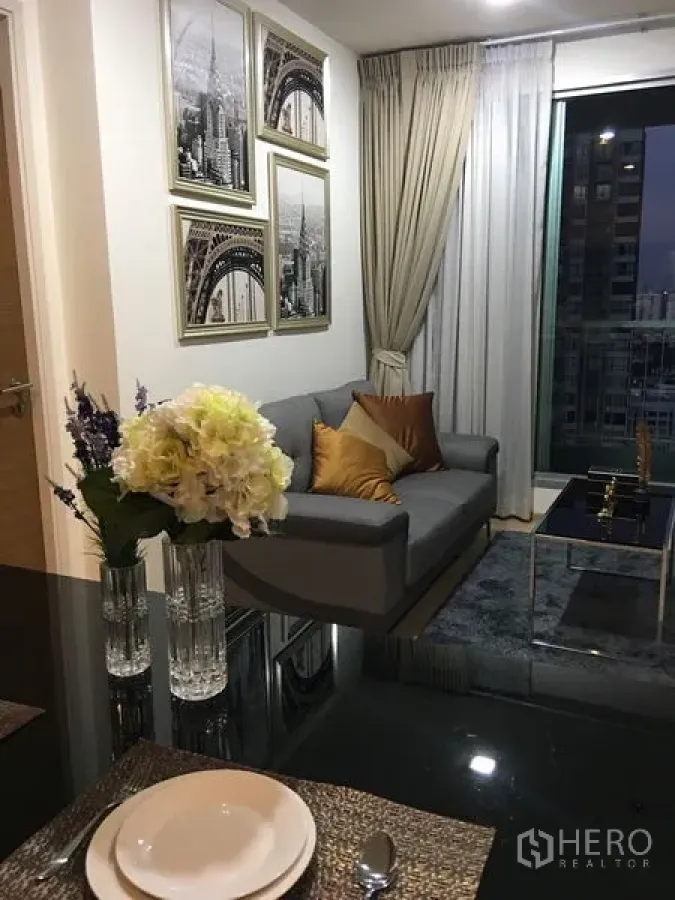 คอนโด ให้เช่าในKhlong Toei, Bangkok - ห้องนั่งเล่นสไตล์โมเดิร์น โซฟาสีเทา งานศิลป์ติดผนัง พรม และหน้าต่างชมวิวเมือง