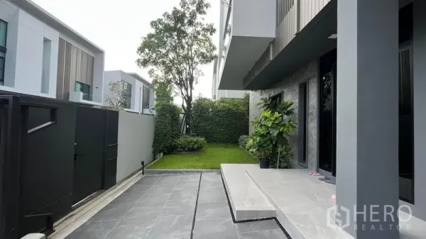 Detached House for sale in Saphan Sung, Bangkok - Private front courtyard with tiled driveway, entry steps and a neat lawn beside a high privacy wall.