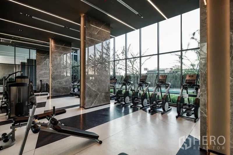 公寓 出租或出售在Phra Khanong, Bangkok - 健身房设有有氧与力量设备，面向落地窗景。