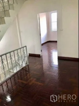 Home Office for rent or sale in Watthana, Bangkok - Bright upstairs landing with polished parquet floors, white walls, staircase and doorway to a bedroom.