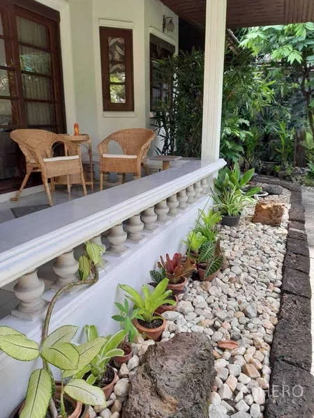 Detached House for rent in Khlong Toei, Bangkok - Covered porch with wicker seating and a pebble-lined planter beside the balustrade.