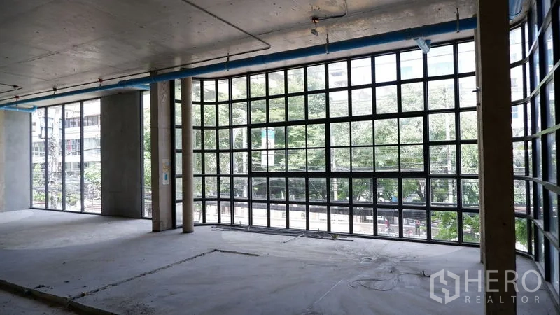 零售空间 出租在Watthana, Bangkok - 转角立面采用大幅网格玻璃，眺望街景与树荫。