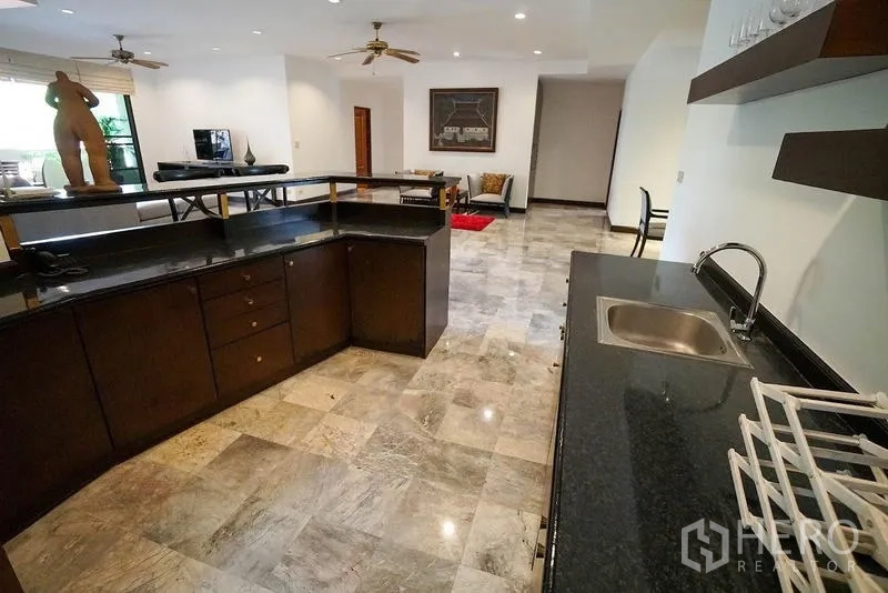 อพาร์ทเมนท์ ให้เช่าในWatthana, Bangkok - เคาน์เตอร์บาร์ครัวหันสู่ห้องนั่งเล่น พร้อมท็อปหินแกรนิตสีเข้มและสตูล