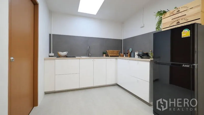ทาวน์เฮาส์ ให้เช่าในKhlong Toei, Bangkok - ครัวมินิมอล ตู้สีขาว ผนังกั้นสีเทา อ่างล้าง และตู้เย็นใต้สกายไลท์