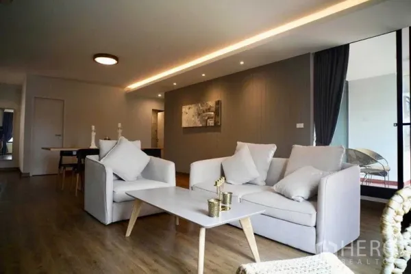 Condominium for rent in Watthana, Bangkok - Open-plan living room with grey sofas, coffee table and balcony access in a Watthana condo.