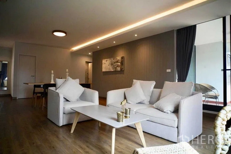 Condominium for rent in Watthana, Bangkok - Open-plan living room with grey sofas, coffee table and balcony access in a Watthana condo.