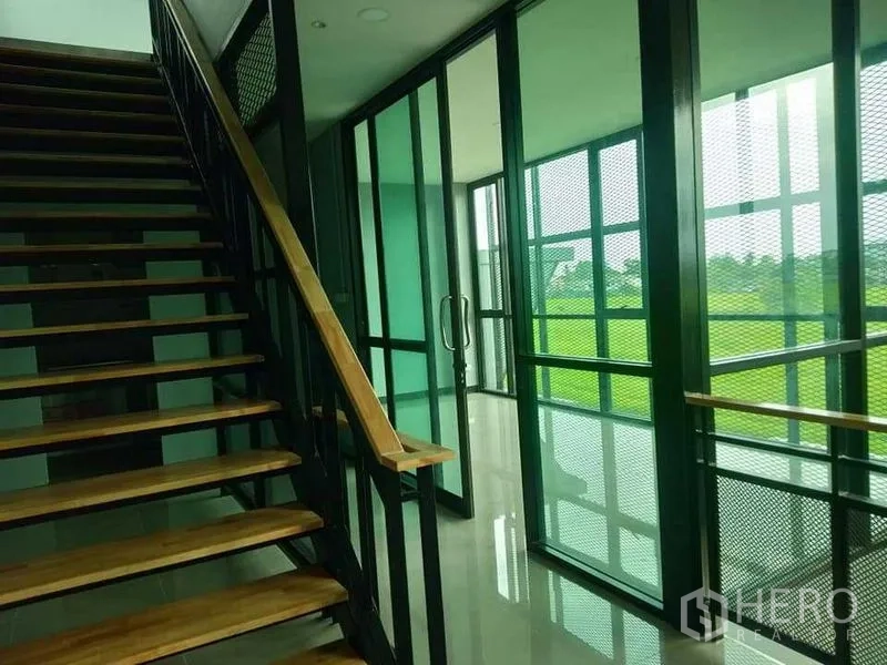 工厂 出租或出售 - 楼梯通往玻璃会议室，金属网面与绿色采光。