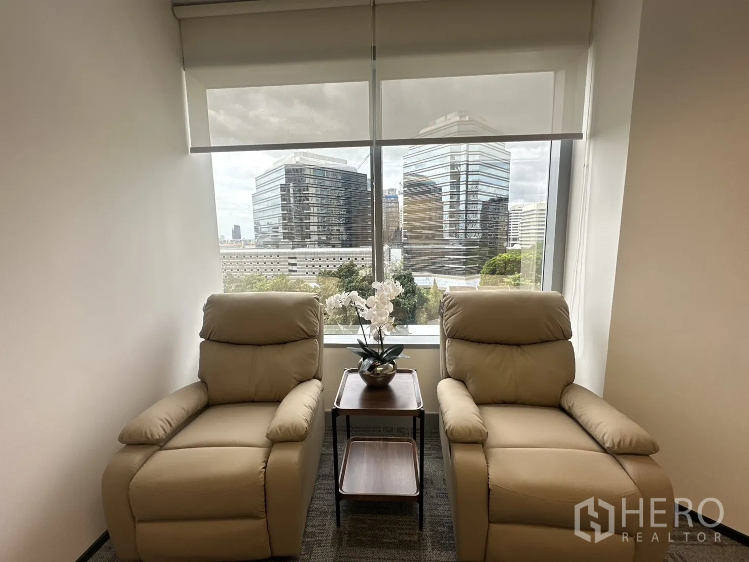 办公室 for rent in Pathum Wan, Bangkok - 两张米色躺椅靠窗而置，可眺望城市天际线。