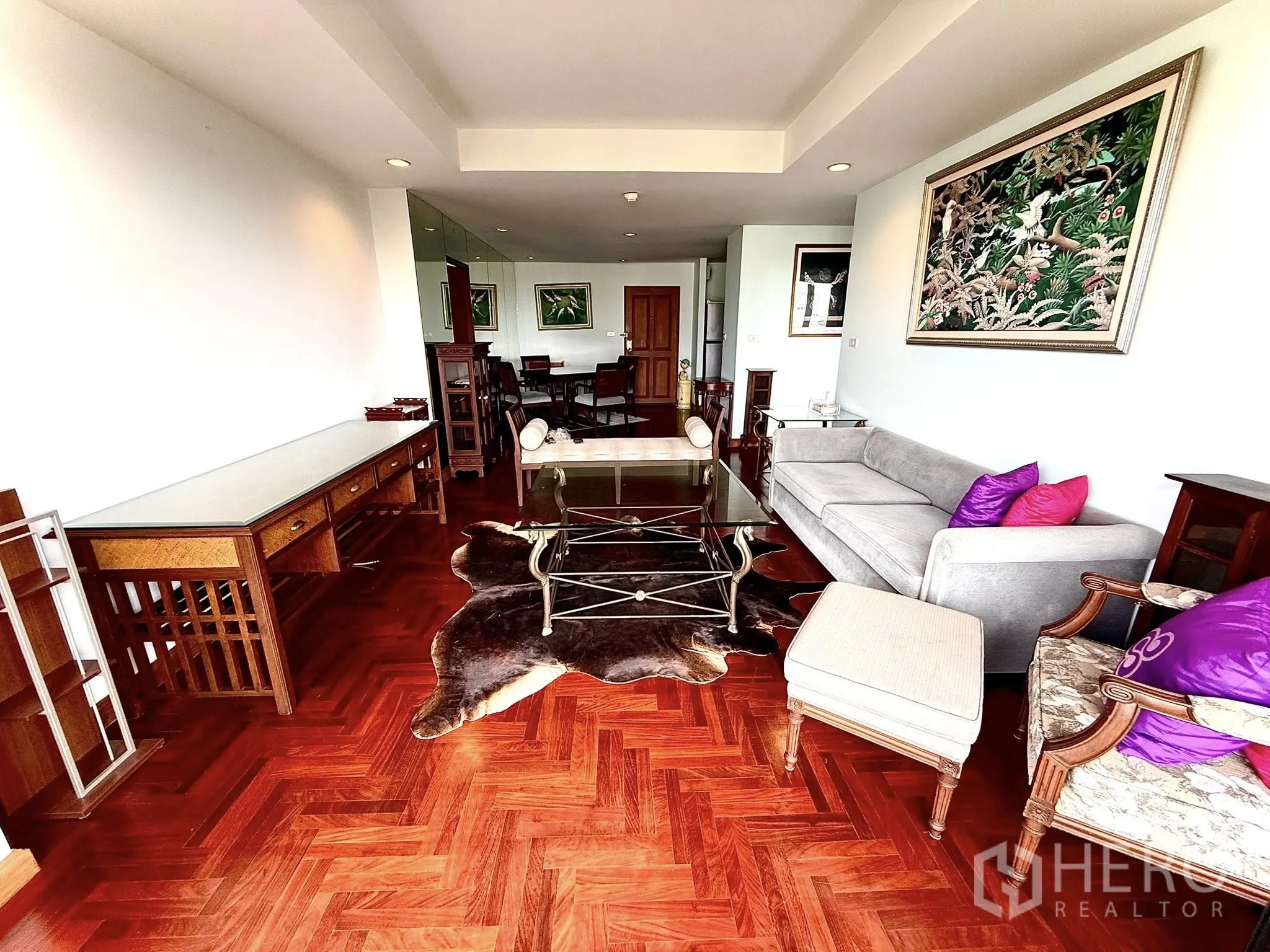 Condominium for rent in Sathon, Bangkok - Spacious lounge with gray sofa, glass coffee table and cowhide rug.