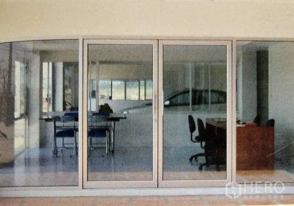 工厂 出租在Ban Phaeo, Samut Sakhon - 厂房内的玻璃隔间办公室，配有桌椅与滑动玻璃门，俯瞰生产区。