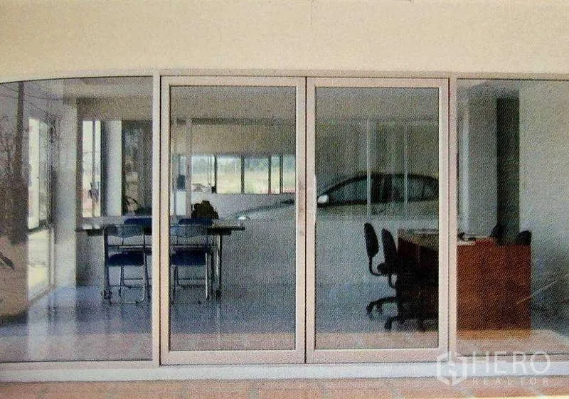 工厂 出租在Ban Phaeo, Samut Sakhon - 厂房内的玻璃隔间办公室，配有桌椅与滑动玻璃门，俯瞰生产区。