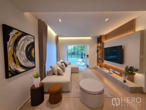 Detached House for rent in Bang Phli, Samut Prakan - Bright open-plan living room with large sofa, TV feature wall and sliding doors to the garden.