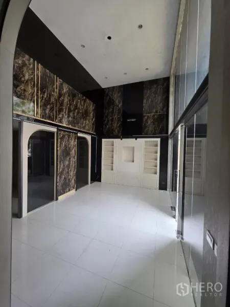 Home Office for rent in Pak Kret, Nonthaburi - High-ceiling lobby with marble accents, built-in shelving and white tiled floors ideal for a showroom.