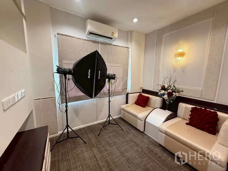 独立式住宅 出售在Bang Khen, Bangkok - 温馨多功能房，沙发与壁灯，摆放摄影灯具可作家庭工作室。