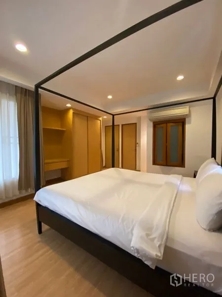 公寓 出租在Watthana, Bangkok - 卧室配四柱床、衣柜及内置梳妆区，暖木色柜体。