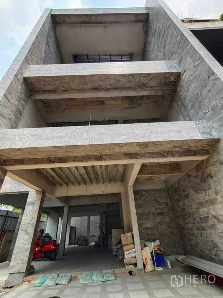 Home Office for rent in Watthana, Bangkok - Multi-storey home office facade with stone cladding and deep balconies under construction.