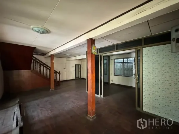 Detached House for rent or sale in Watthana, Bangkok - Ground-floor living area with wooden columns, staircase and dark wood floors.