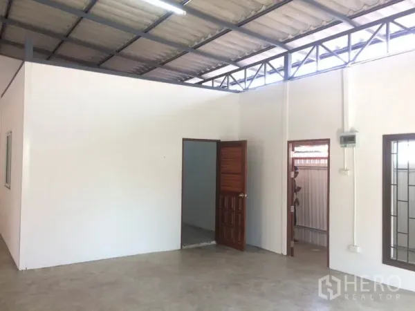 货栈 出租在Pathum Thani - 仓库内分隔的办公室区域，带窗与门，位于钢结构屋顶下方。