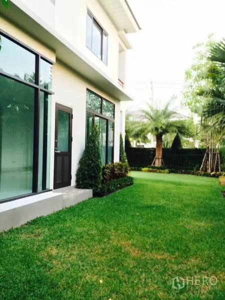 บ้าน ขายในLat Krabang, Bangkok - มุมด้านข้างบ้านเดี่ยวสองชั้นสไตล์โมเดิร์น กระจกบานใหญ่และสนามหญ้า